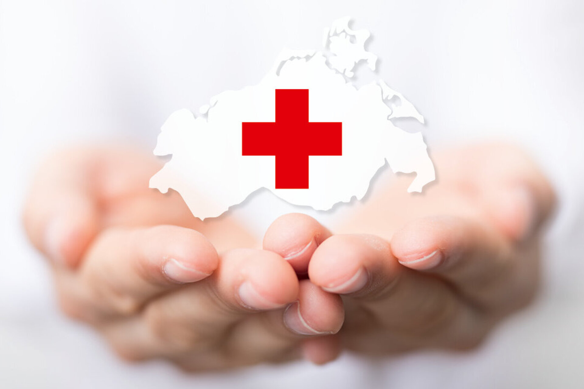 Hände halten Umriss von Deutschland mit rotem Kreuz als Symbol des Deutschen Roten Kreuzes